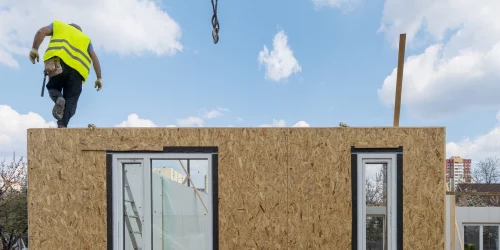 Man in Hi-vis walking along a modular building structure