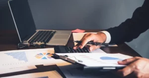 office desk with financial documents on it and a man calculating finances
