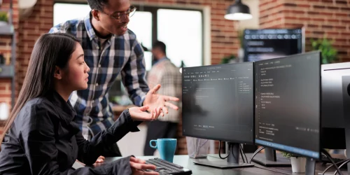 Man and woman looking at two monitors in an office setting