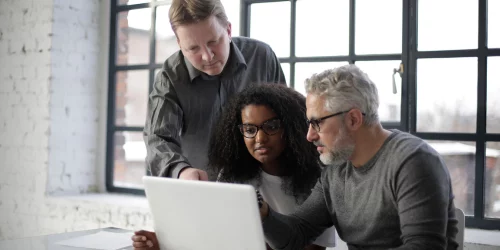 3 people talking around a computer