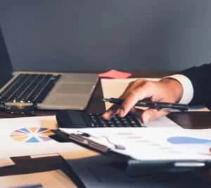 office desk with financial documents on it and a man calculating finances
